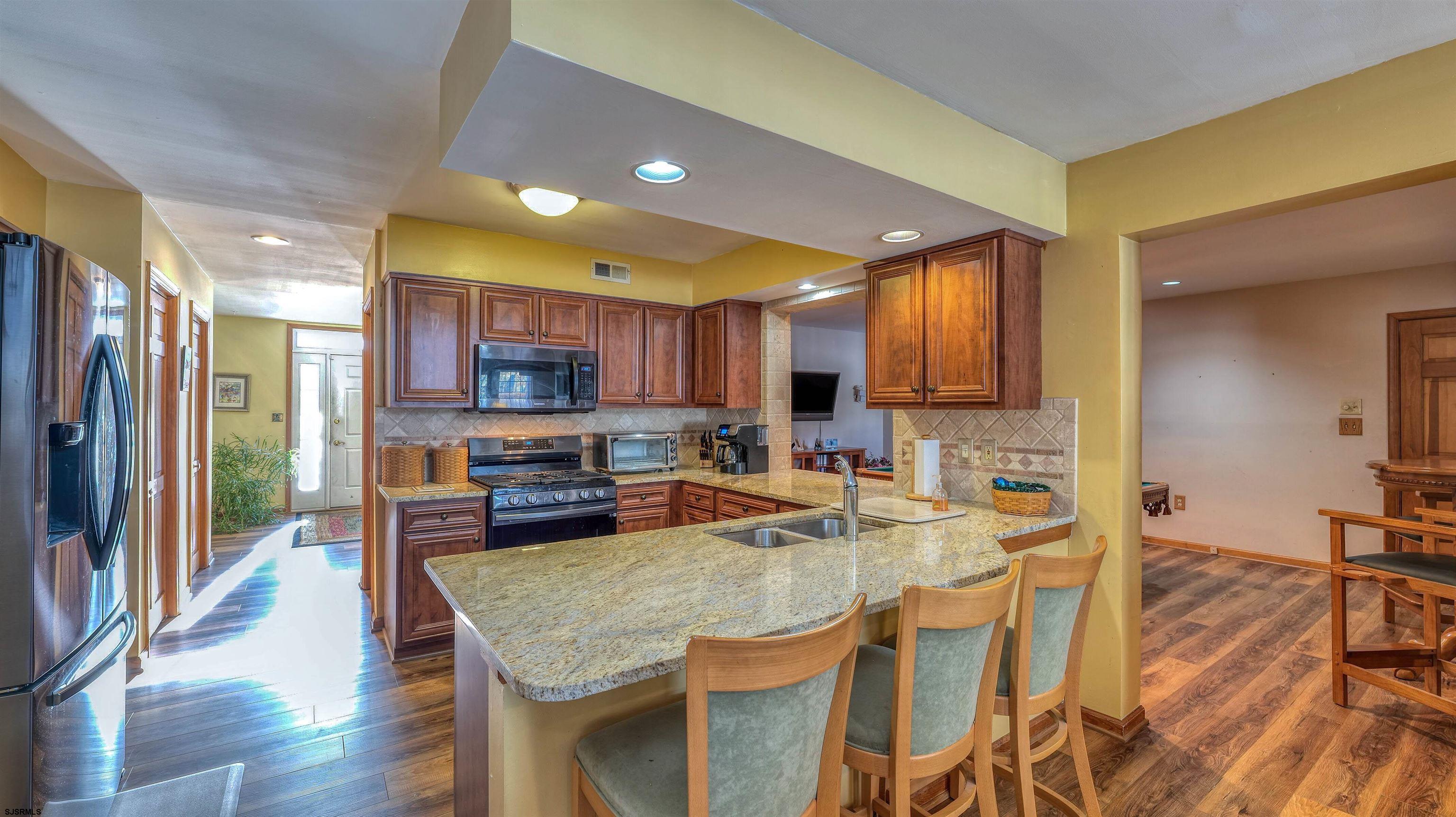627 East Seaview Ridge Drive Galloway Township, NJ 08205 - Photo 18 of 50 a kitchen with stainless steel appliances granite countertop a refrigerator a stove top oven and a dining table with wooden floor