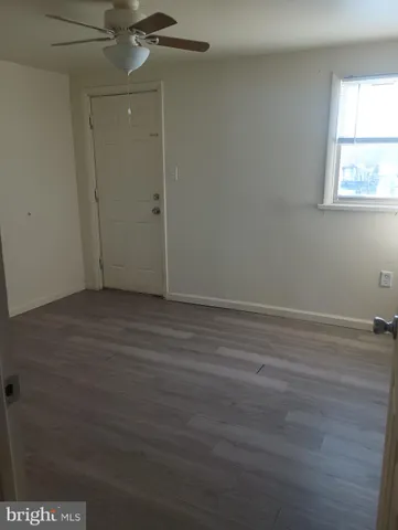 an empty room with wooden floor closet and windows