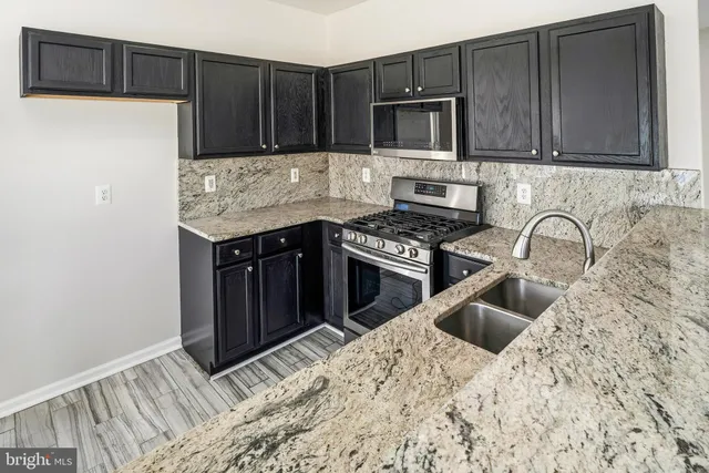 a kitchen with granite countertop a stove a microwave a sink and a refrigerator