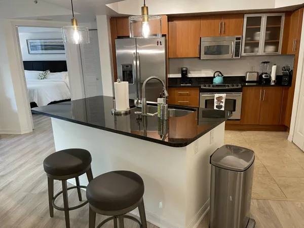 a kitchen with stainless steel appliances granite countertop a sink a refrigerator and wooden cabinets