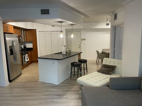 a kitchen with stainless steel appliances kitchen island granite countertop a table chairs and a refrigerator