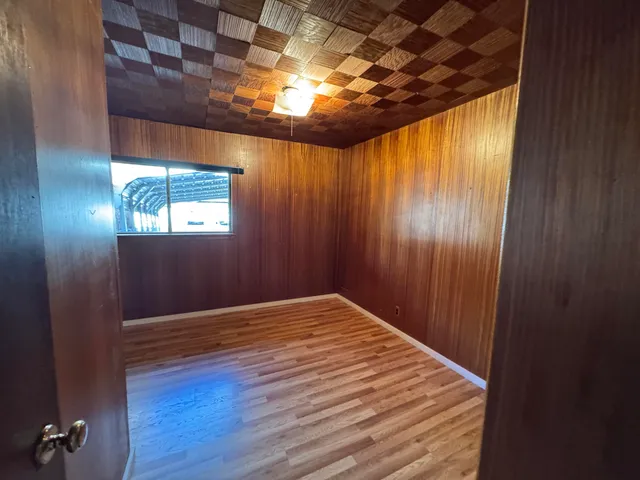 a view of an empty room with wooden floor and windows