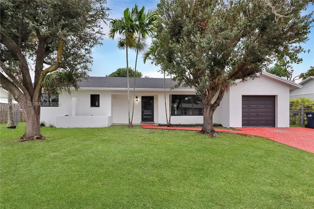 a front view of a house with a garden and tree