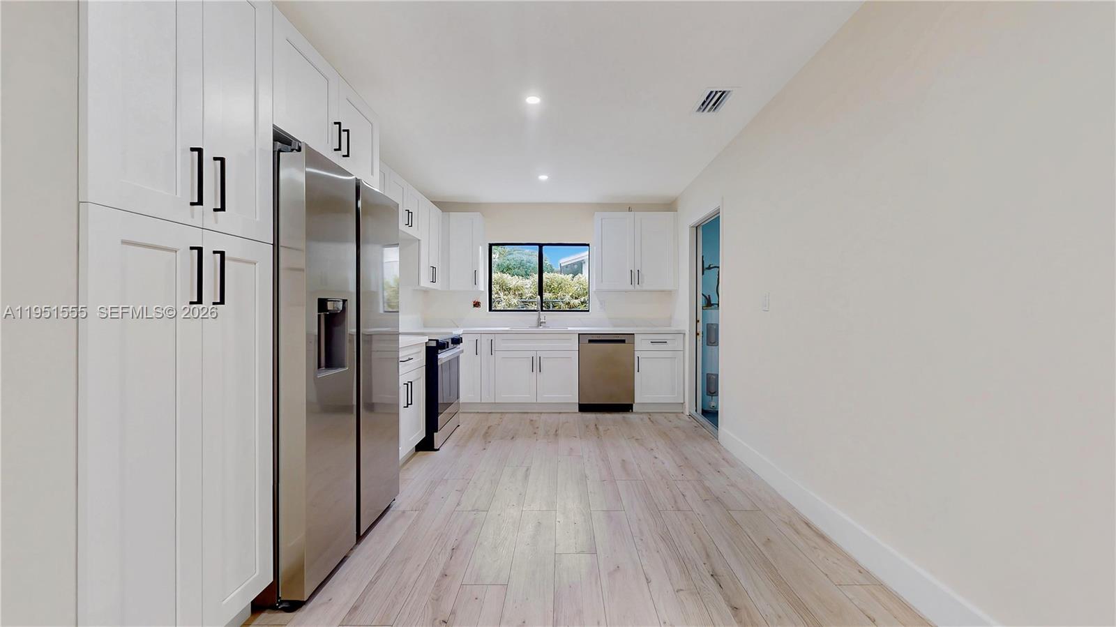 10944 Southwest 159th Terrace Miami, FL 33157 - Photo 8 of 25 a kitchen with white cabinets and wooden floor