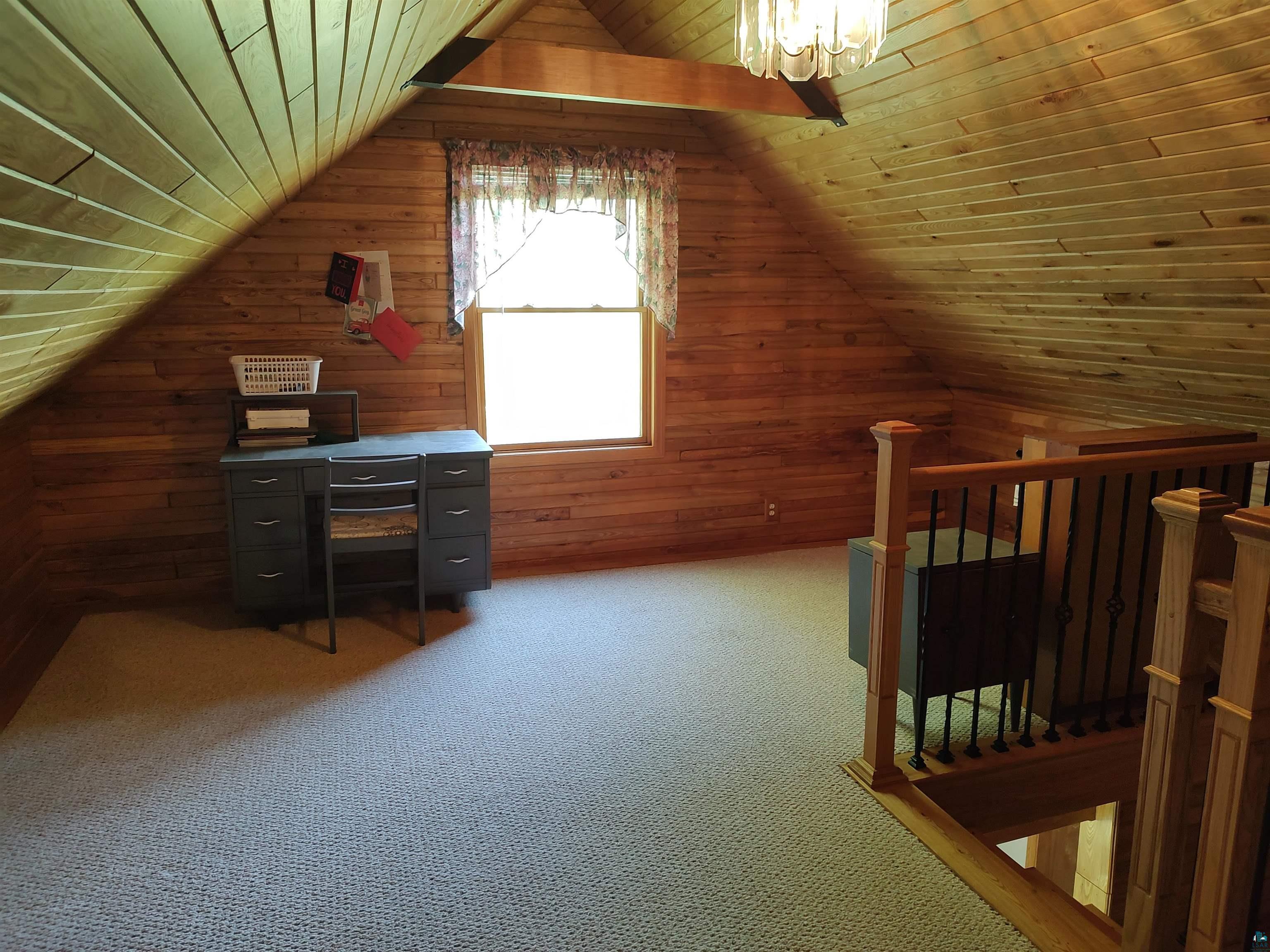 2585 Hautala Road Iron River, WI 54847 - Photo 10 of 28 Attic space featuring wood-paneled walls and ceiling, a window with natural light, and neutral-toned carpeting