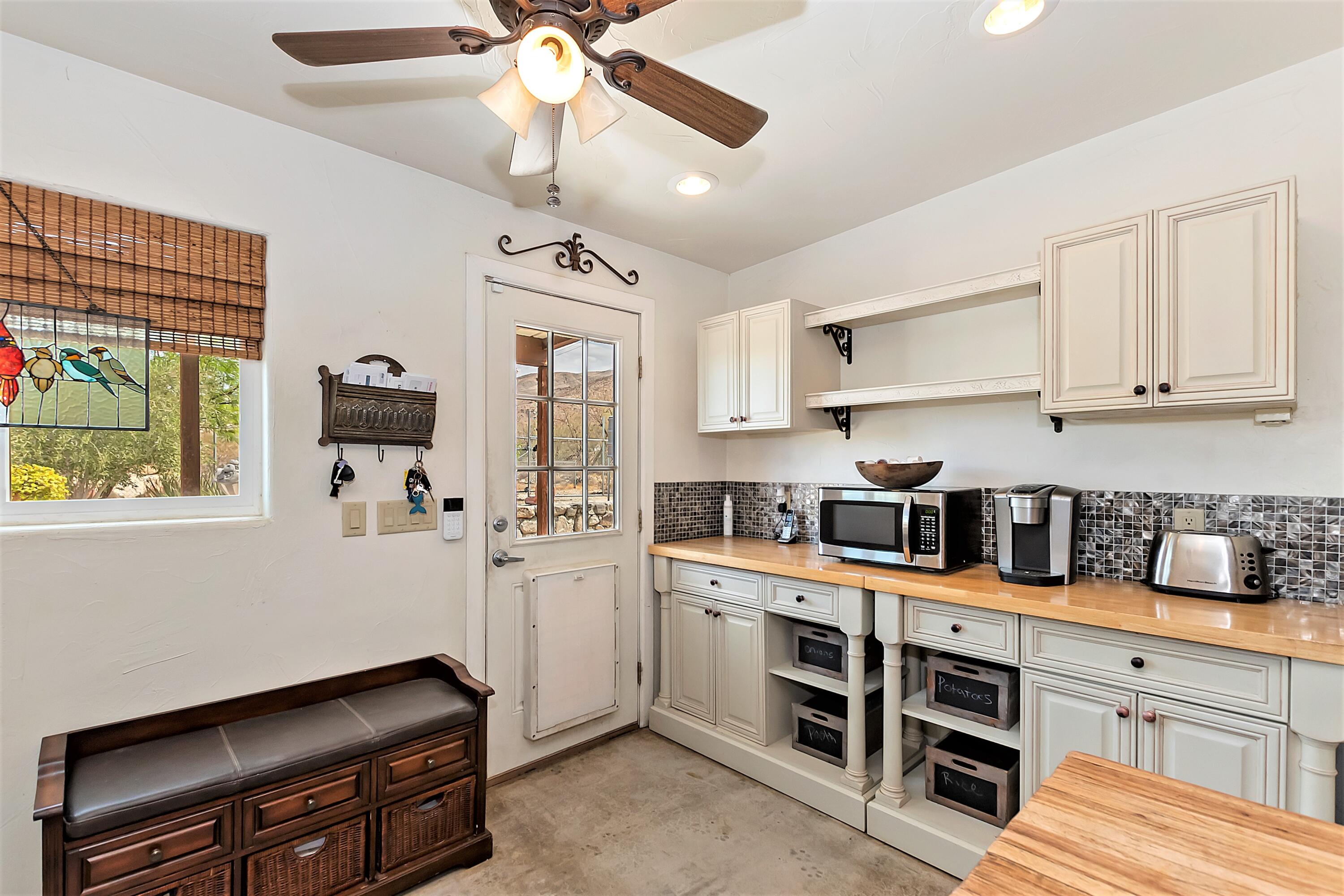 73315 Helms Road Desert Hot Springs, CA 92241 - Photo 18 of 41 a kitchen with stainless steel appliances kitchen island granite countertop a refrigerator a stove a sink dishwasher and white cabinets with wooden floor