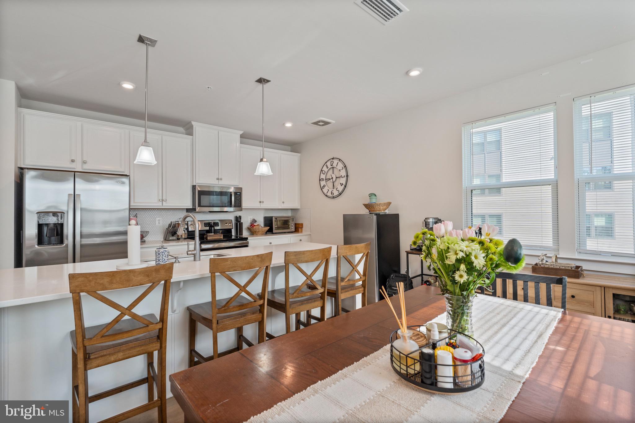 a kitchen with stainless steel appliances granite countertop a dining table chairs and white cabinets