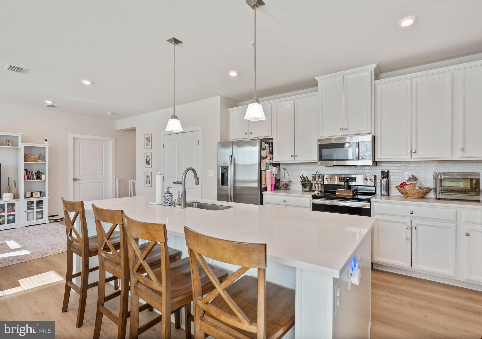 10411 Resort Road, Unit B Ellicott City, MD 21042 - Photo 20 of 36 a kitchen with stainless steel appliances granite countertop a stove top oven a refrigerator a sink and white cabinets with wooden floor