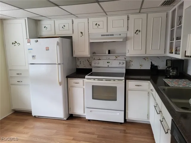 a kitchen with white cabinets and white appliances