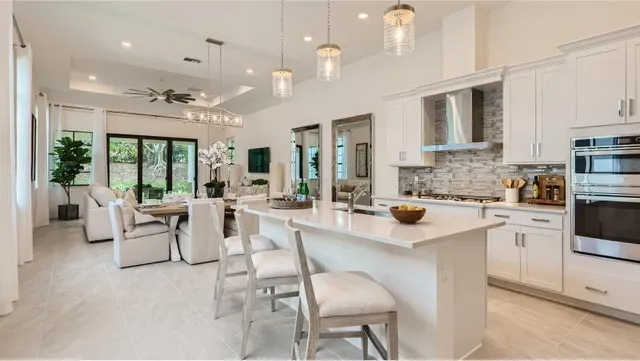 a large white kitchen with lots of counter space and chandelier