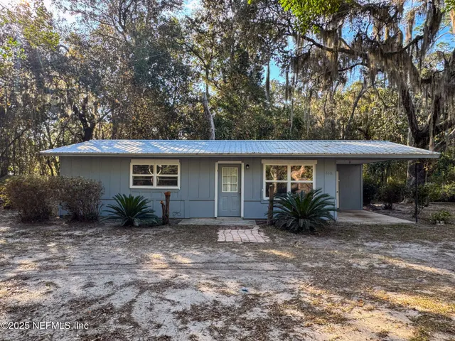 a front view of house with yard and trees around