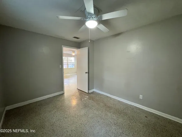 an empty room with windows and fan