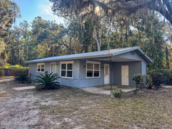 a front view of house with yard and trees in the background