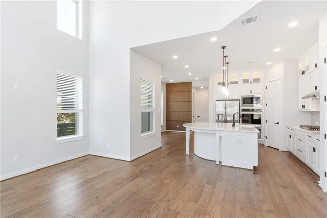 a large white kitchen with lots of counter space wooden floor and appliances