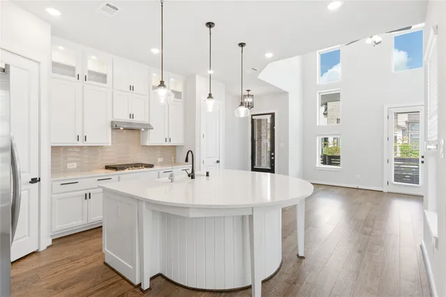 a large white kitchen with a refrigerator a sink dishwasher a stove and white cabinets with wooden floor