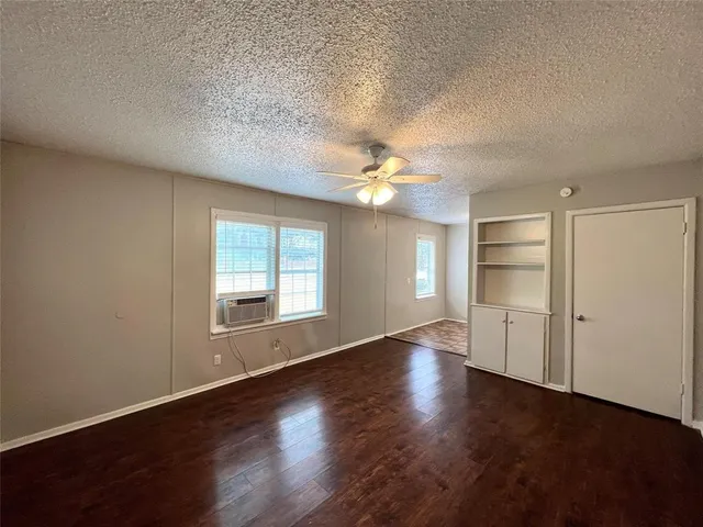 an empty room with wooden floor chandelier and windows