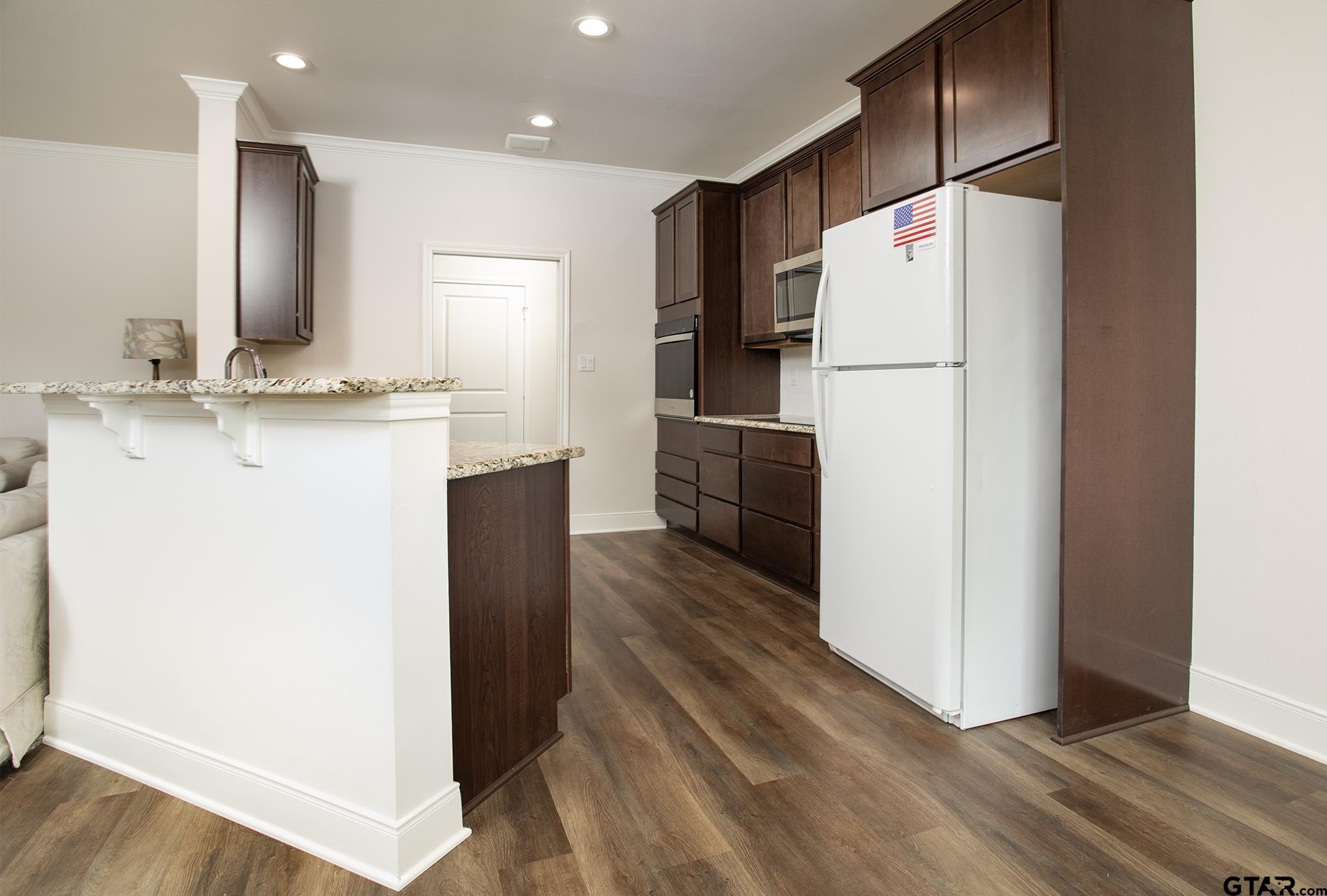 6143 Hamilton Mdws Way Tyler, TX 75703 - Photo 6 of 29 a kitchen with kitchen island a refrigerator a counter top and wooden floor