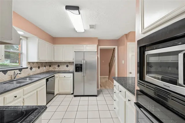 a kitchen with a refrigerator sink and cabinets