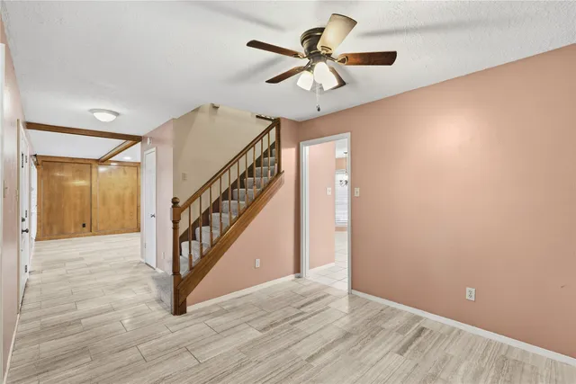 a view of an empty room with wooden floor and a ceiling fan
