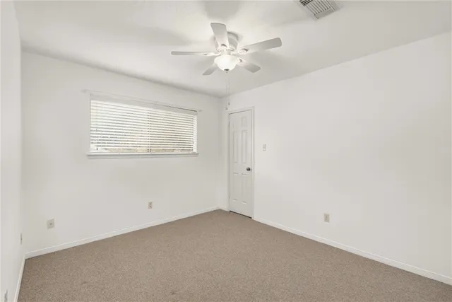 an empty room with a chandelier fan and windows