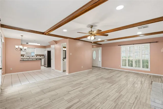 a view of an empty room with wooden floor and a kitchen