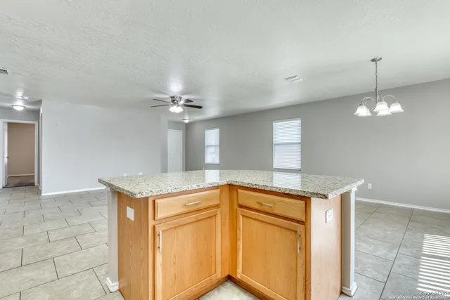 a kitchen with stainless steel appliances granite countertop a sink a refrigerator and chandelier