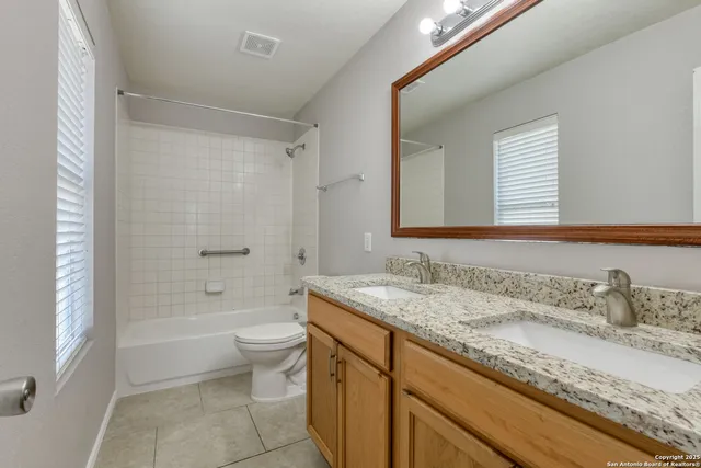 a bathroom with a granite countertop sink a toilet and shower