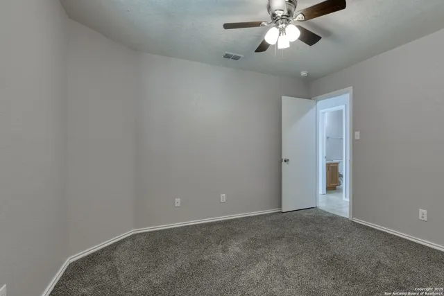 a view of an empty room and chandelier fan