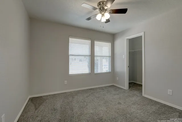 an empty room with windows and fan