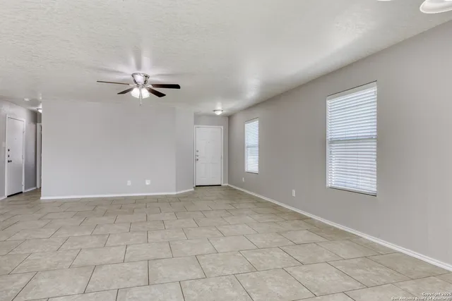 an empty room with windows and fan