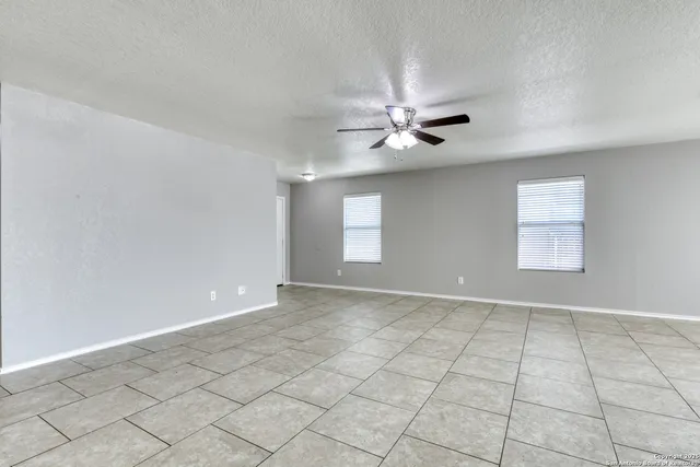an empty room with windows and ceiling fan