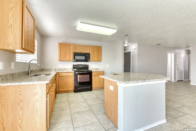 a kitchen with a stove a sink a microwave and a refrigerator