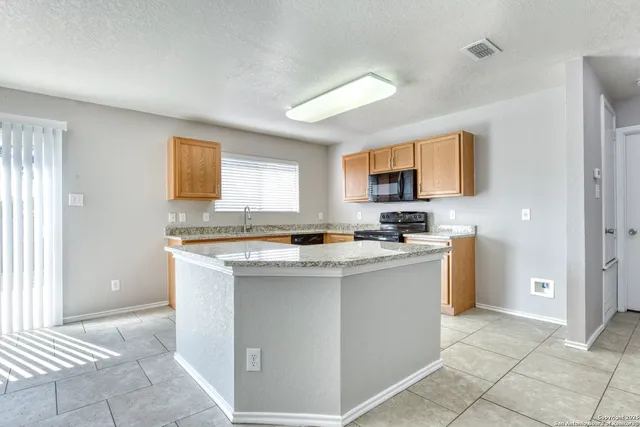 a kitchen with stainless steel appliances granite countertop a stove top oven a sink a refrigerator and a counter space