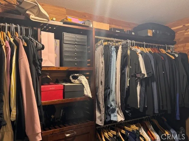a view of walk in closet with clothes and shoes