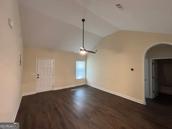 a view of an empty room with a window and wooden floor