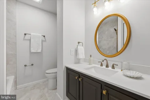a bathroom with a granite countertop double vanity sink toilet and a mirror