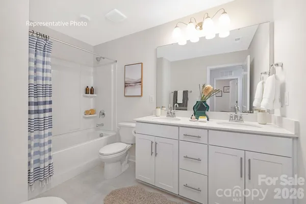 a bathroom with a double vanity sink toilet mirror and bathtub