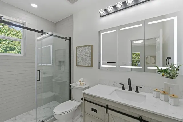 a bathroom with a sink toilet vanity and shower