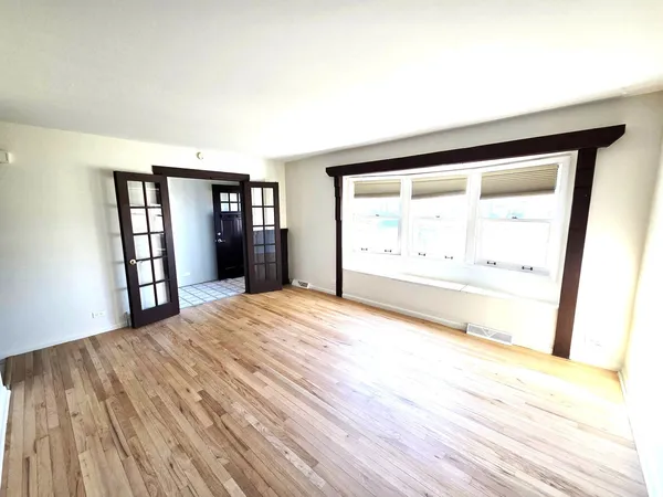 a view of empty room with wooden floor and fan