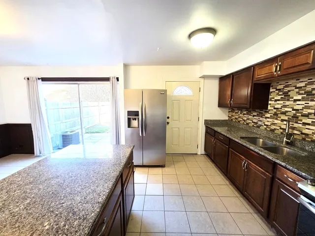 a kitchen with granite countertop a refrigerator and a sink