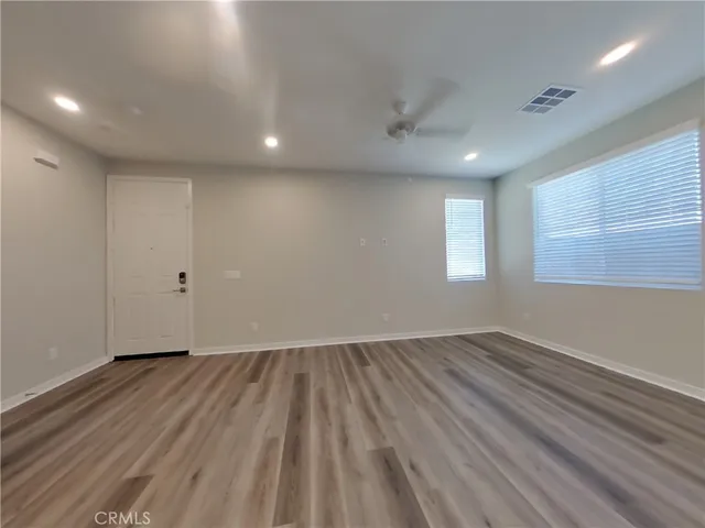 an empty room with wooden floor and windows