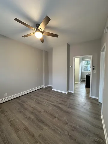 an empty room with wooden floor fan and windows