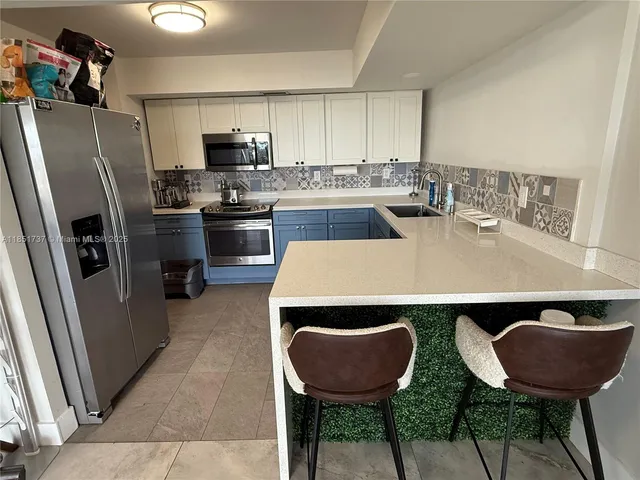 a kitchen with a refrigerator a microwave a sink and chairs