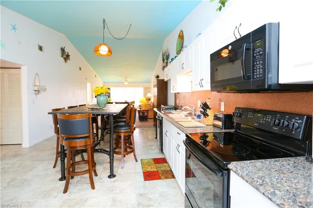 a kitchen with stainless steel appliances granite countertop a stove a sink dishwasher and a dining table with wooden floor