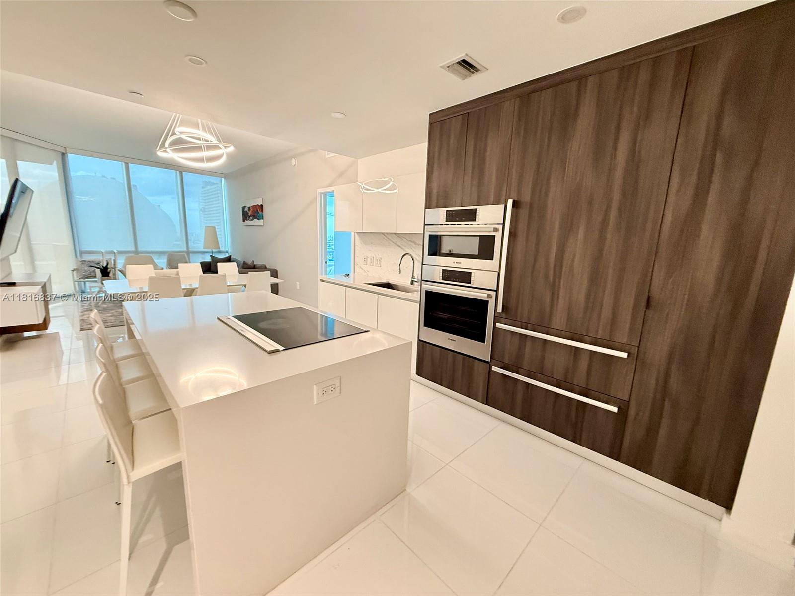 851 Northeast 1st Avenue, Unit 1108 Miami, FL 33132 - Photo 6 of 42 a kitchen with kitchen island a stove a sink and a refrigerator with wooden floor