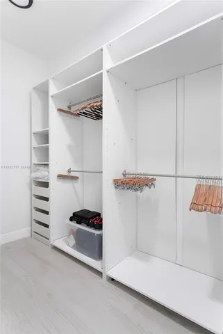a view of walk in closet with clothes and shoes