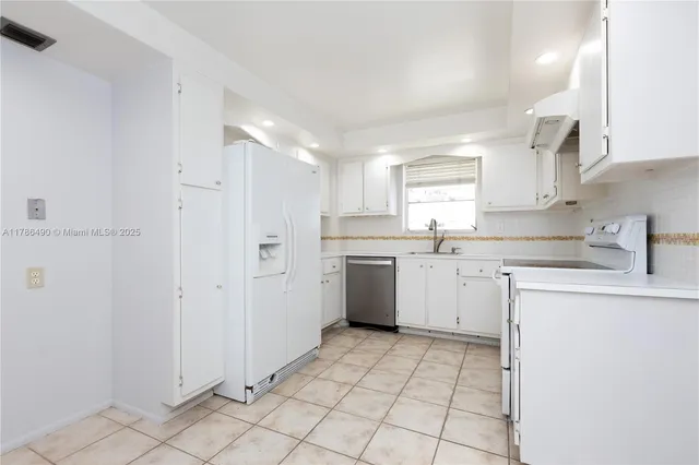 a kitchen with white cabinets a sink stove and refrigerator