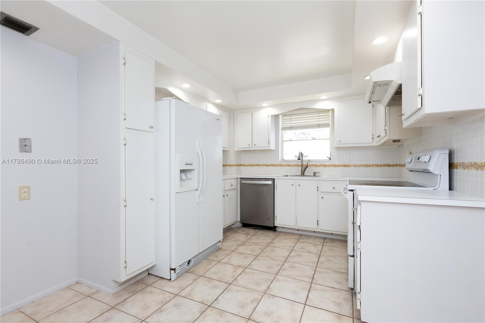 2750 Northeast 183rd Street, Unit 511 Aventura, FL 33160 - Photo 5 of 36 a kitchen with white cabinets a sink stove and refrigerator