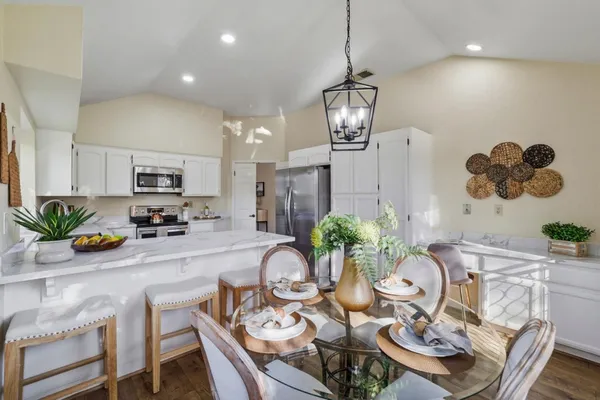 a view of a dining room and kitchen with furniture wooden floor and a chandelier