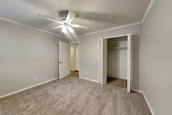 an empty room with closet and a chandelier fan